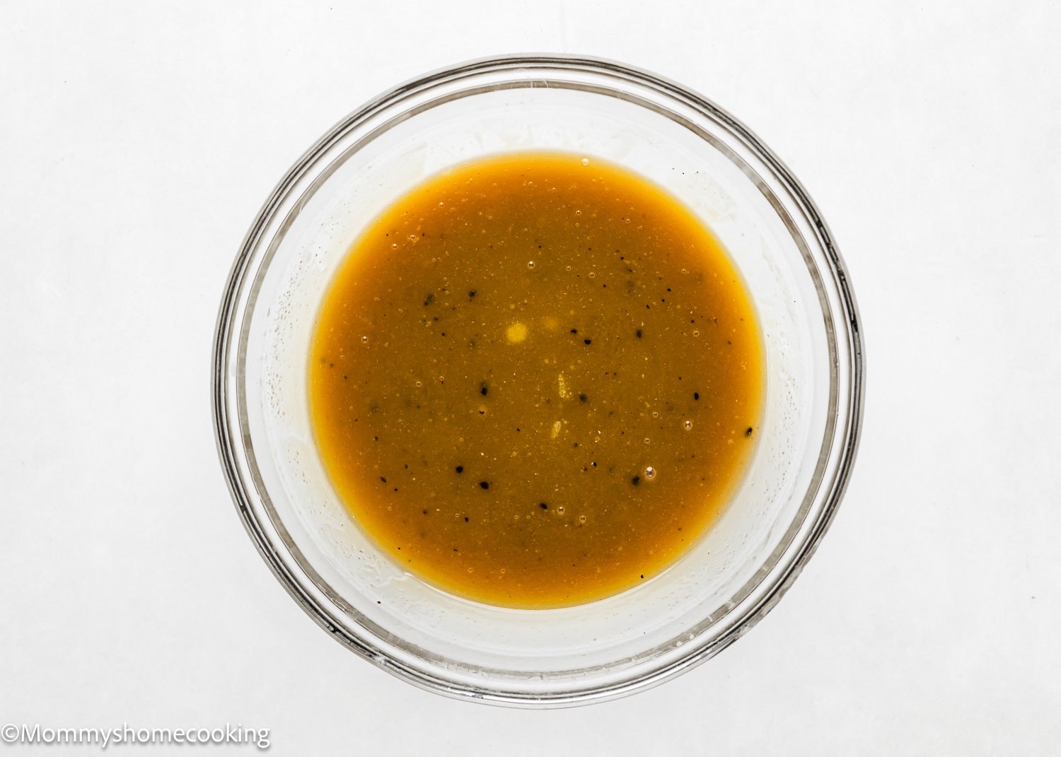 A glass bowl contains wet ingredients to make the best eggless brookies.