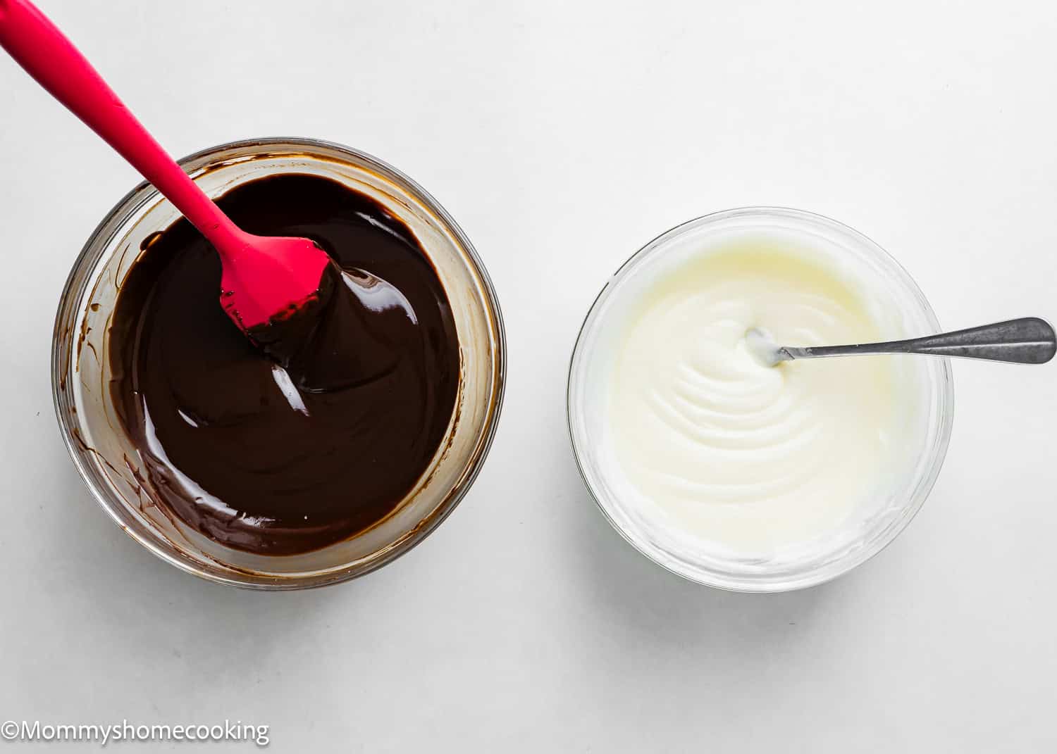 Two bowls on a white surface: one with chocolate frosting for donuts and a red spatula, the other with sugar glaze and a spoon. Perfect for creating the best eggless cake donuts—quick and easy!.