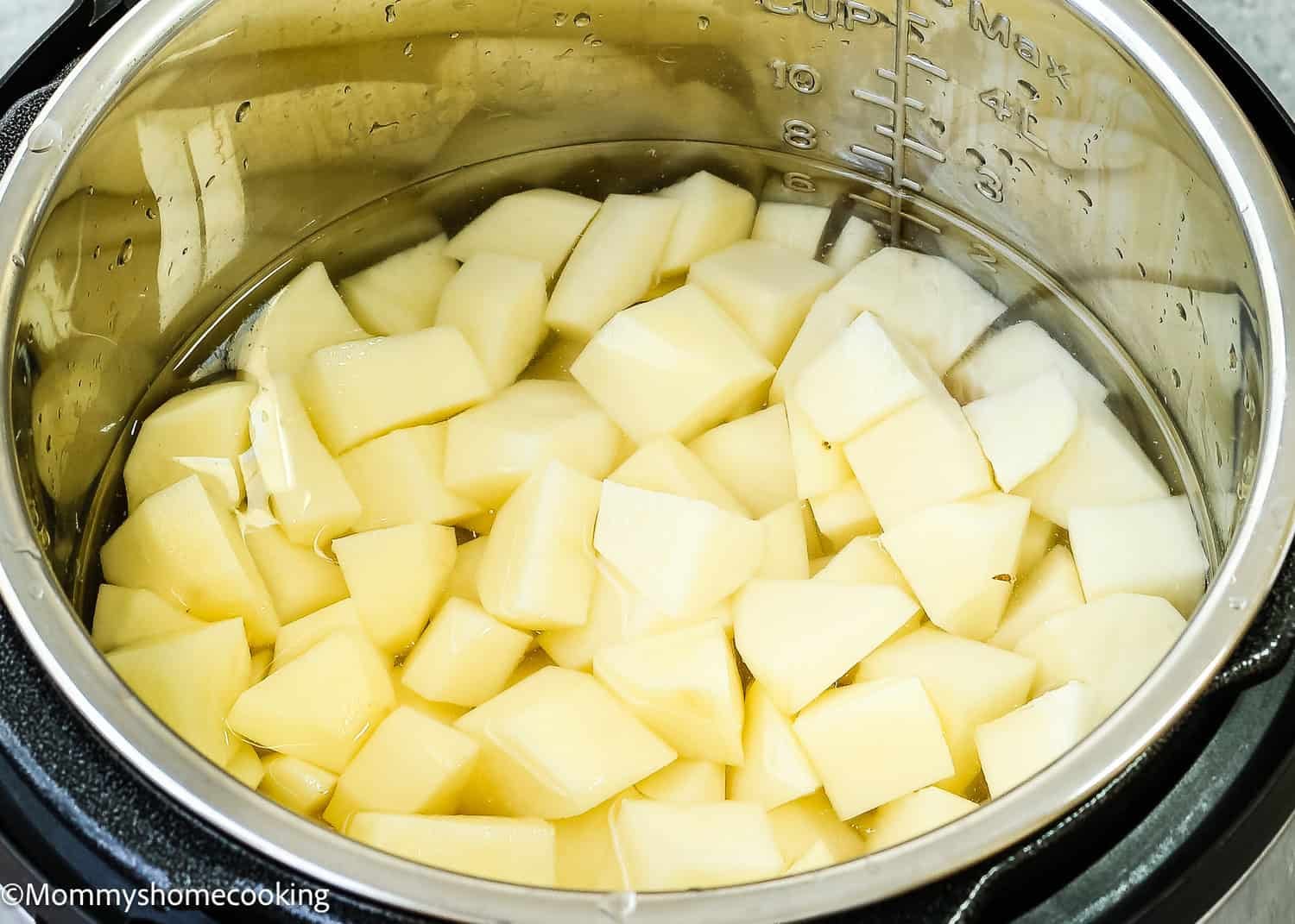 Cubed potatoes soaking in water inside a stainless steel pot, ready to transform into an easy creamy mashed potatoes recipe that's smooth with no lumps.