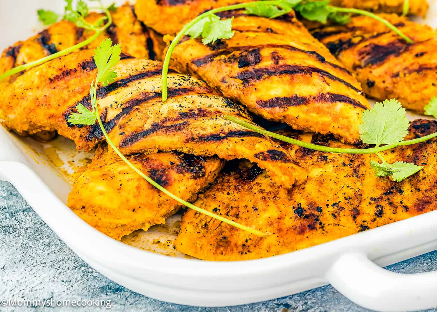 Enjoy easy chicken shawarma with grilled chicken fillets seasoned with aromatic spices and elegantly garnished with fresh cilantro, all presented in a pristine white dish.