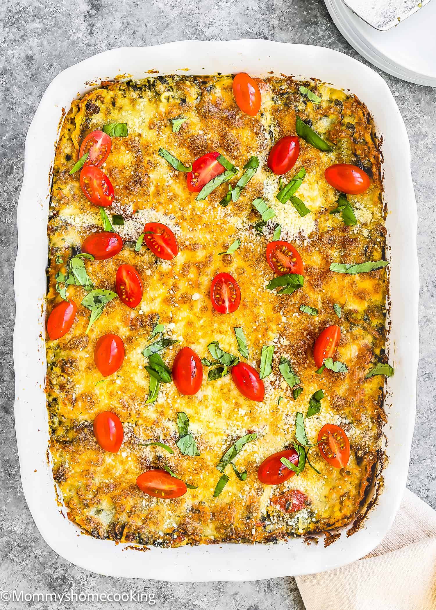 Easy White Turkey Lasagna: a delectable baked casserole featuring layers of tender turkey, topped with melted cheese, cherry tomatoes, and chopped herbs, all presented in a pristine white dish.