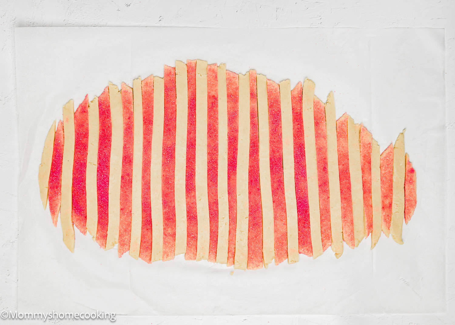Eggless Valentine's Striped Sugar Cookies feature strips of red and white dough arranged in an abstract oval pattern on a plain white surface.