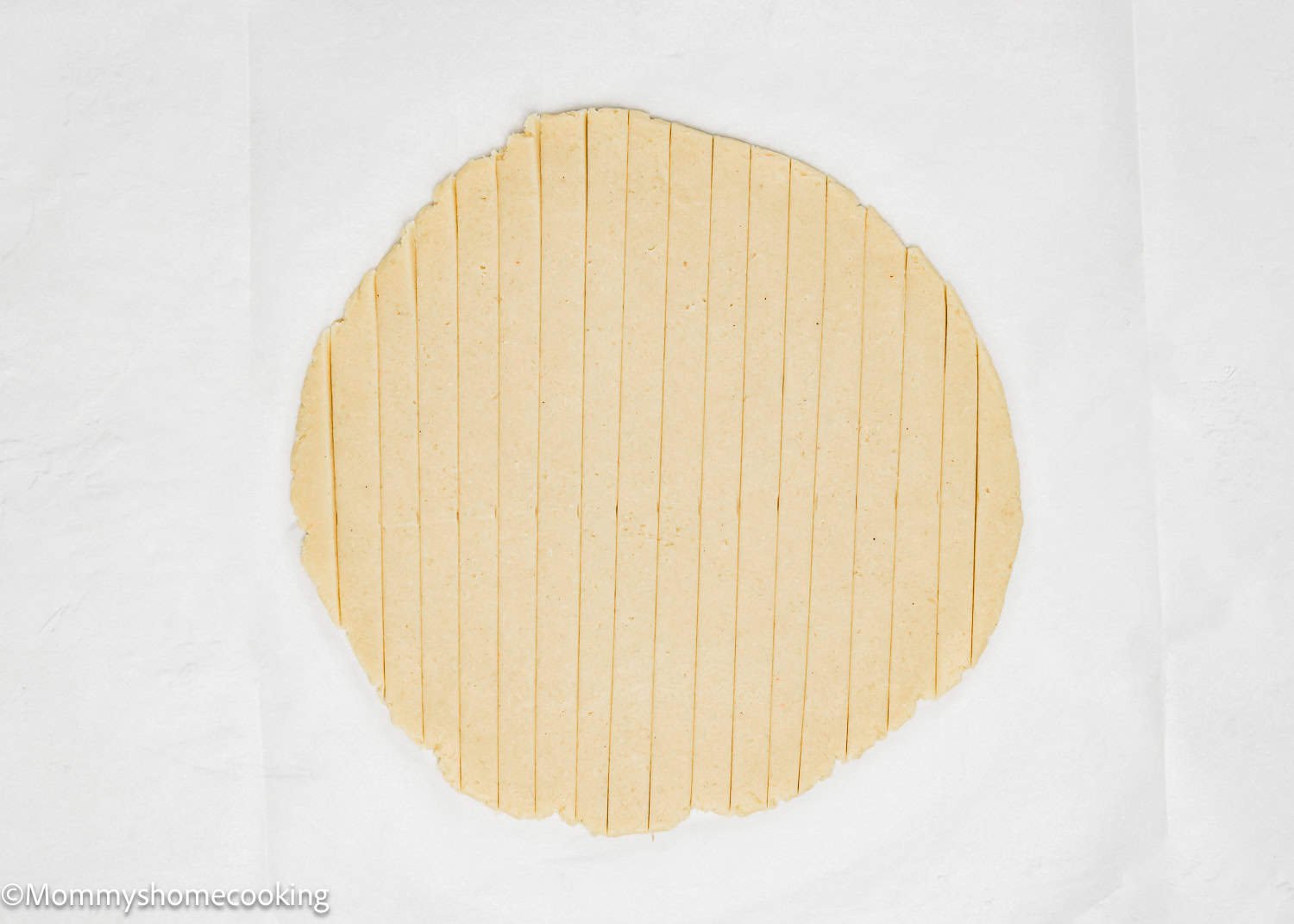 A sheet of rolled-out dough transforms into perfectly spaced vertical strips on a white surface, setting the stage for our delightful Eggless Valentine's Striped Sugar Cookies.