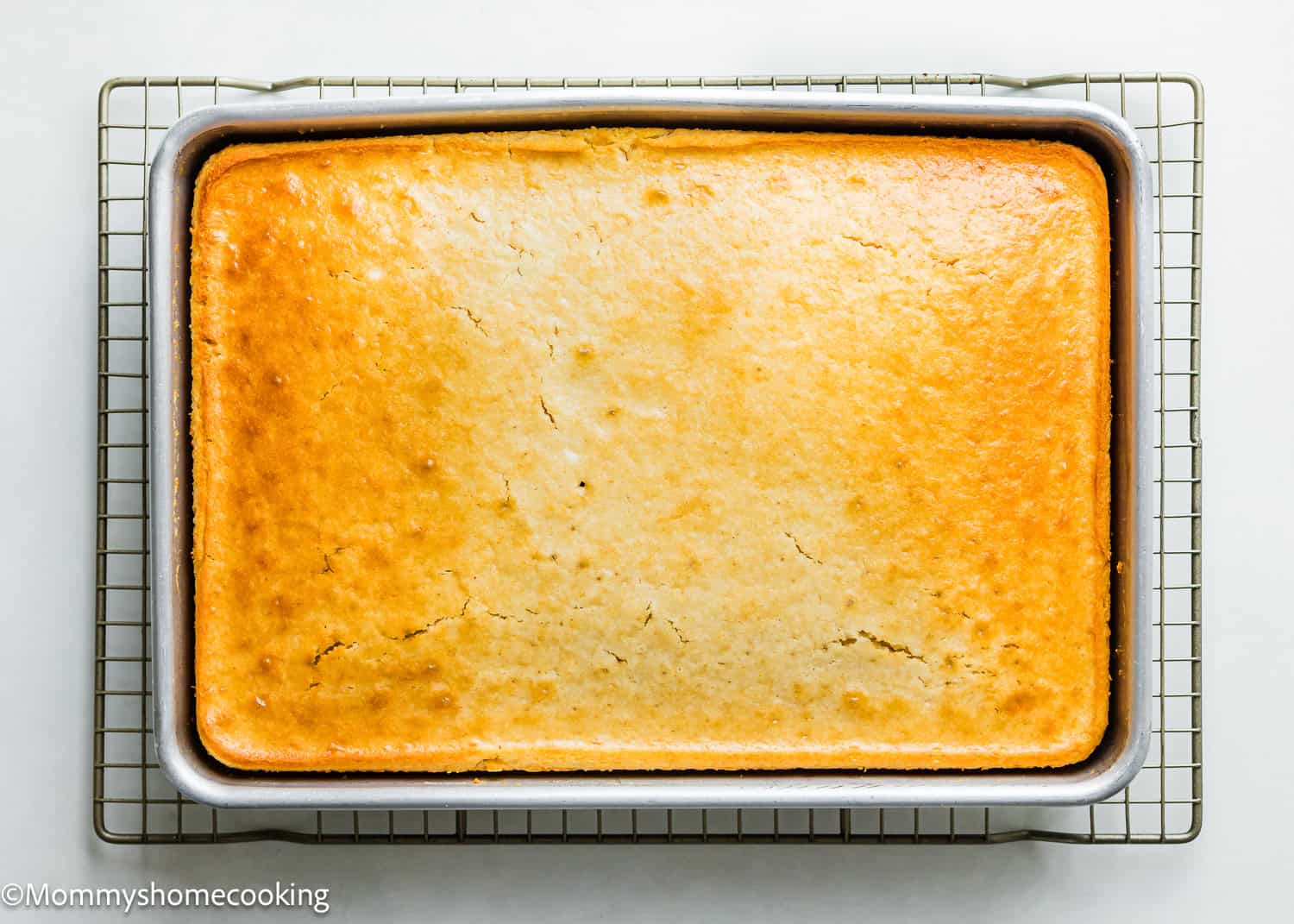 Easy, golden baked egg-free and dairy-free vanilla sheet cake in a rectangular pan resting on a cooling rack.