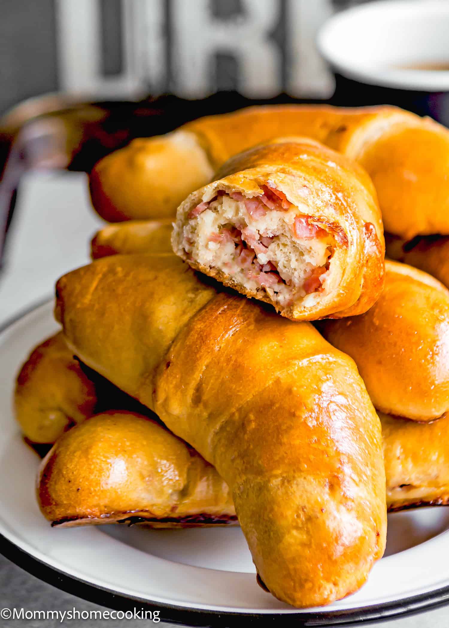 A plate of golden-brown Venezuelan Cachitos , with one on top revealing a savory filling of chopped ham.