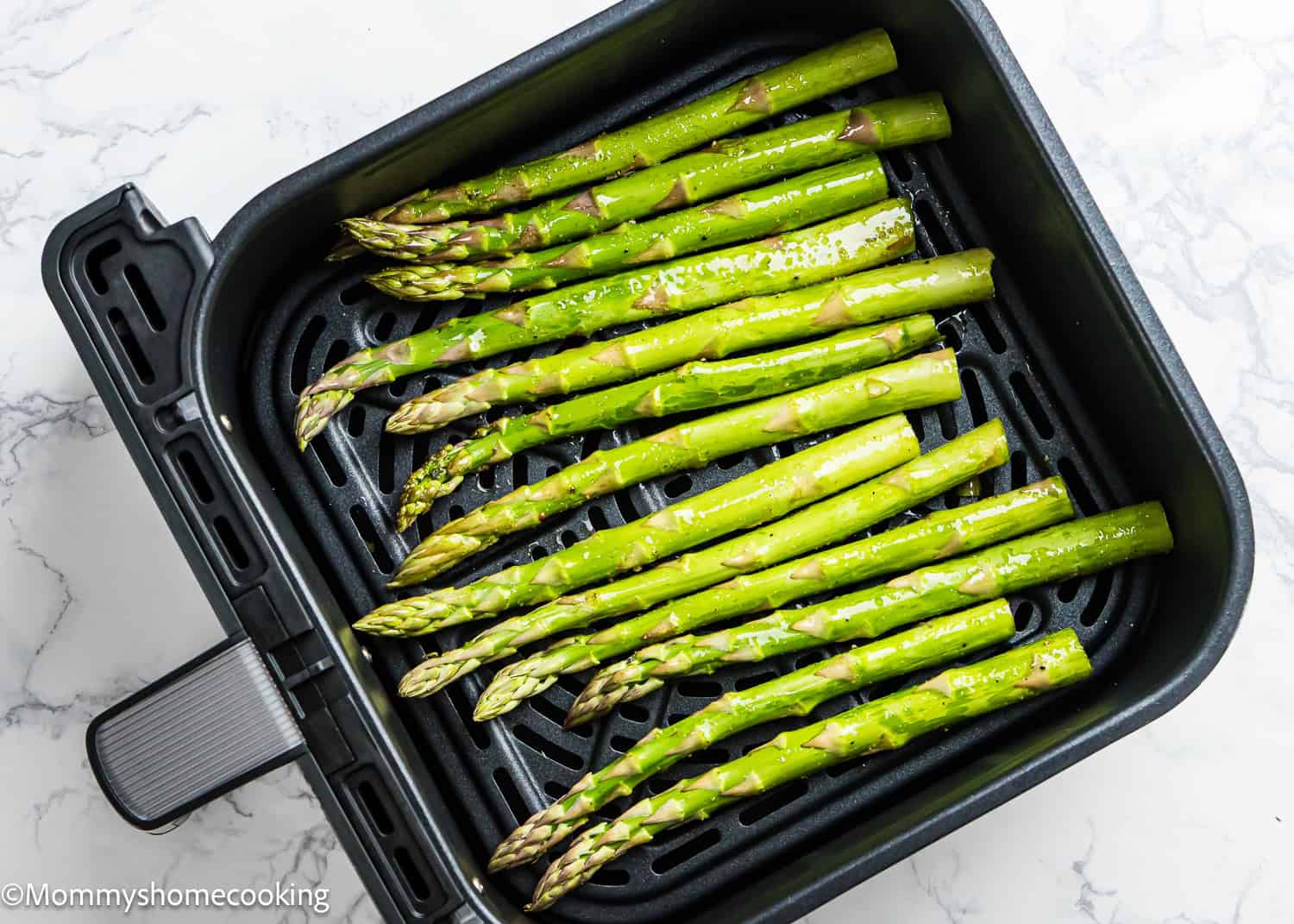 Perfect Air Fryer Asparagus awaits as fresh asparagus spears are artfully arranged in the air fryer basket, ready for cooking.