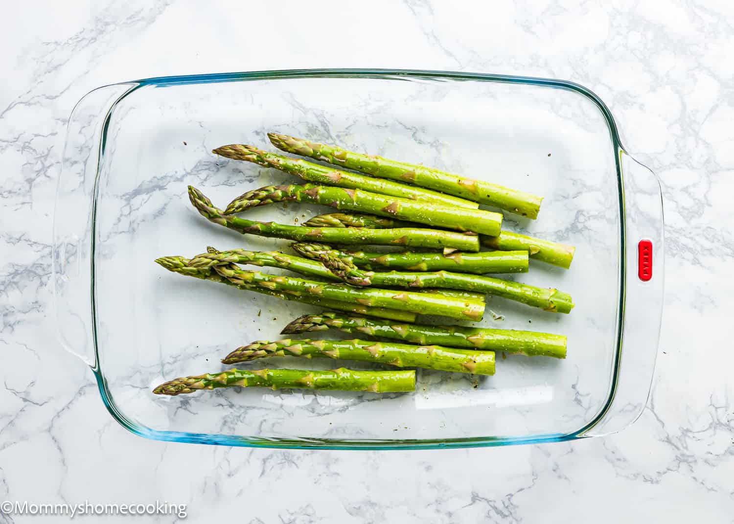 Perfect Air Fryer Asparagus rests elegantly in a glass dish on a marble surface, showcasing fresh, raw spears ready for culinary magic.