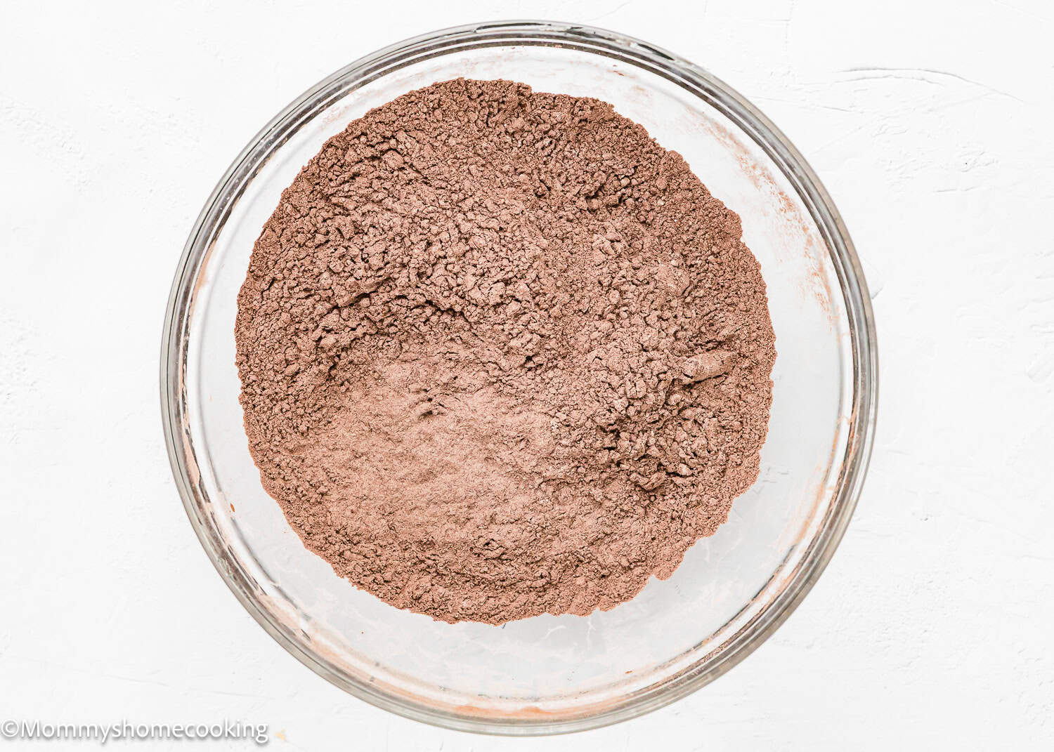 A glass bowl filled with dry ingredients, ready to enhance your Eggless Chocolate Zucchini Muffins.