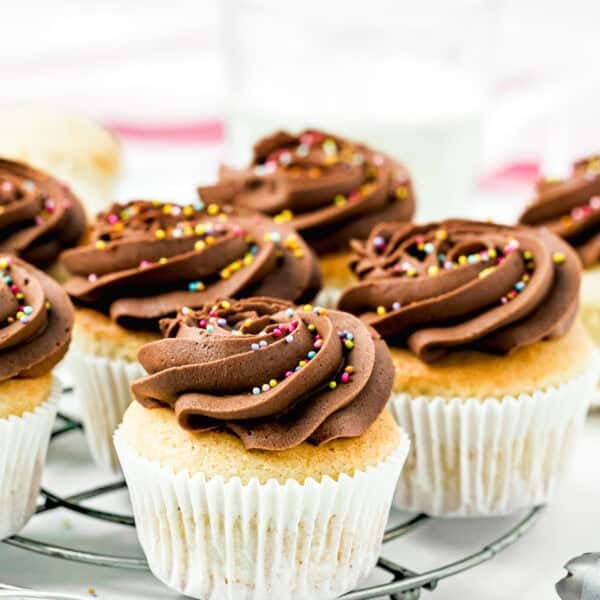 Vanilla cupcakes with chocolate frosting and colorful sprinkles sit on a wire rack, showcasing how simple swaps from The Ultimate Guide to Egg Substitutes in Baking can still deliver sweet perfection.
