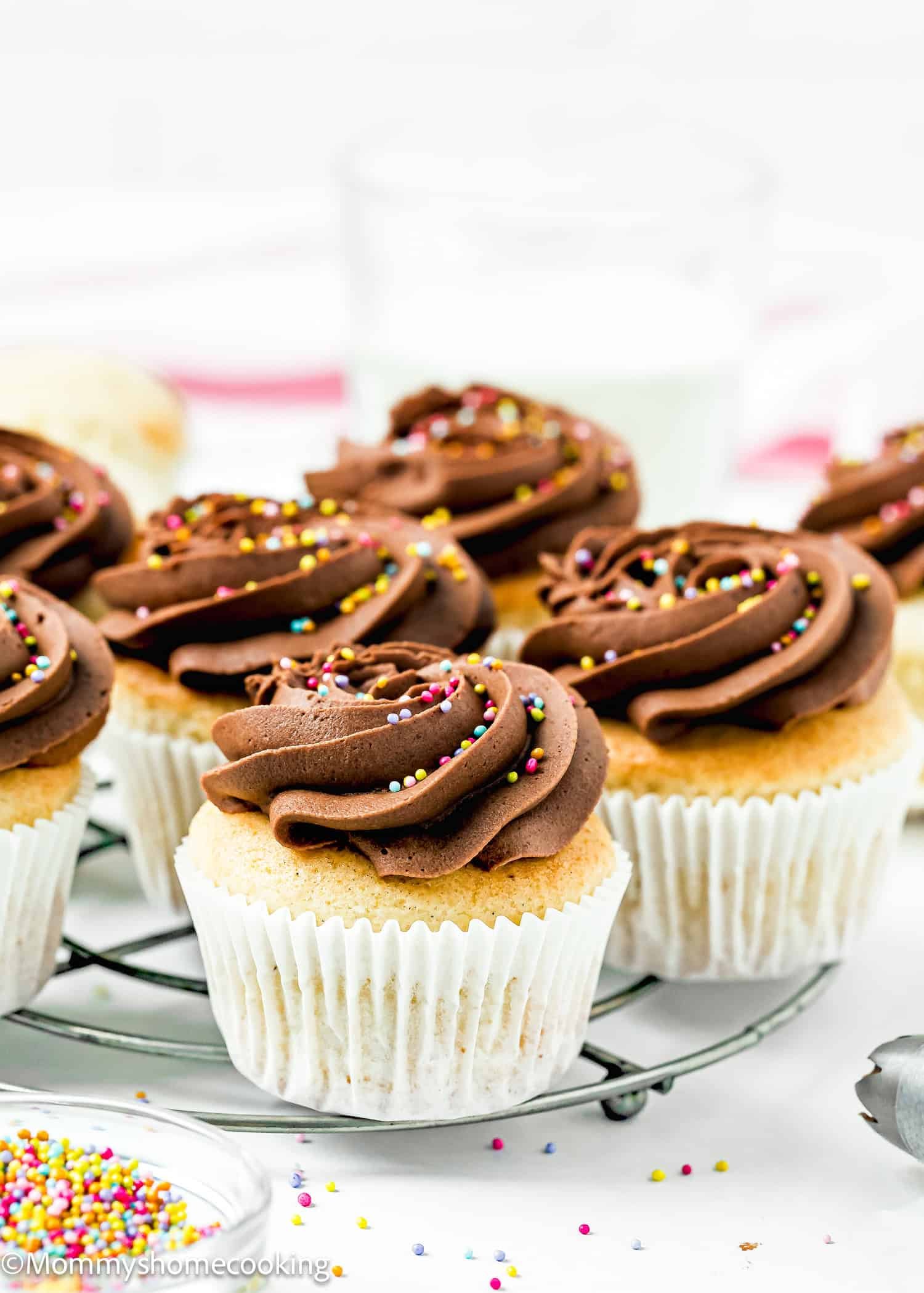 Vanilla cupcakes with chocolate frosting and colorful sprinkles sit on a wire rack, showcasing how simple swaps from The Ultimate Guide to Egg Substitutes in Baking can still deliver sweet perfection.