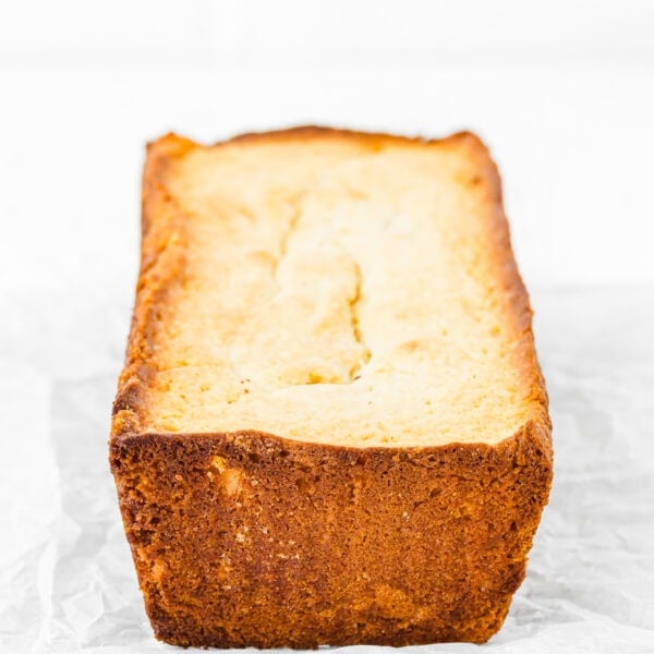 A loaf of freshly baked bread with a golden-brown crust sits on a cooling rack lined with parchment paper, showcasing the success of troubleshooting egg-free baking to perfection.