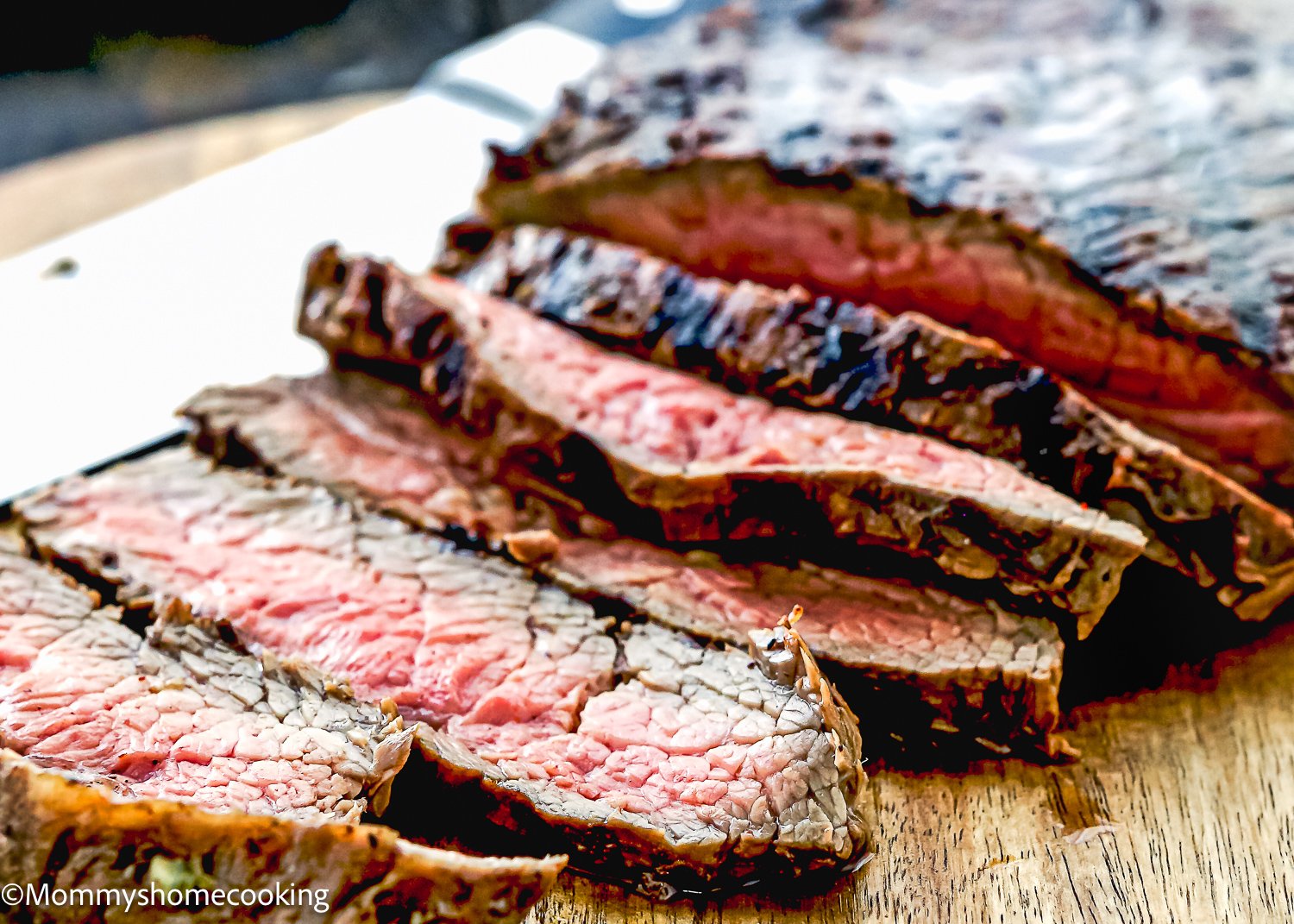 Easy Carne Asada with the best marinade ever, featuring sliced grilled steak on a wooden board, showcasing a seared exterior and pink interior.