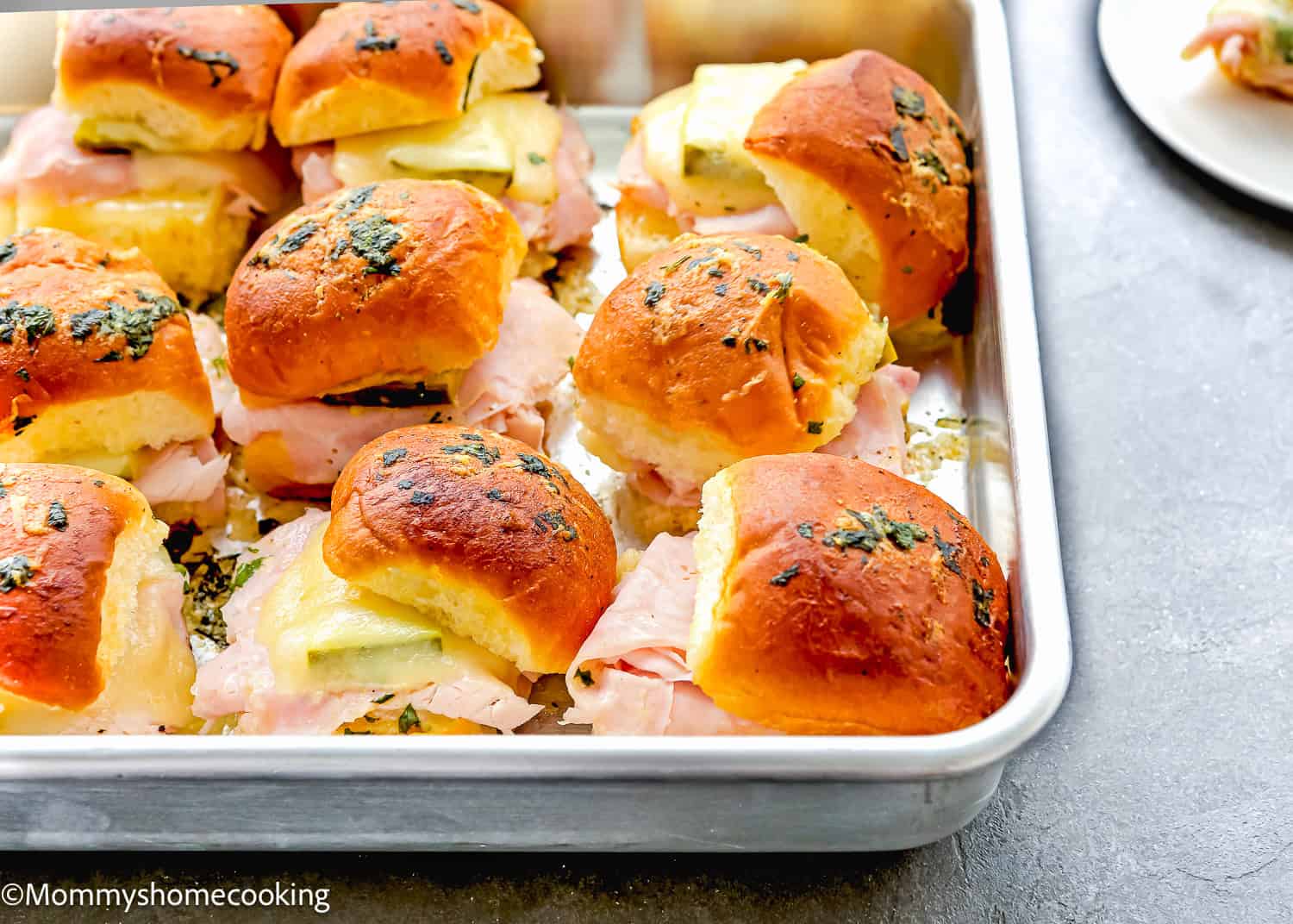 Easy Cuban sliders loaded with ham, cheese, and herbs sit perfectly on baked buns in a metal tray. Ready in just 30 minutes!.