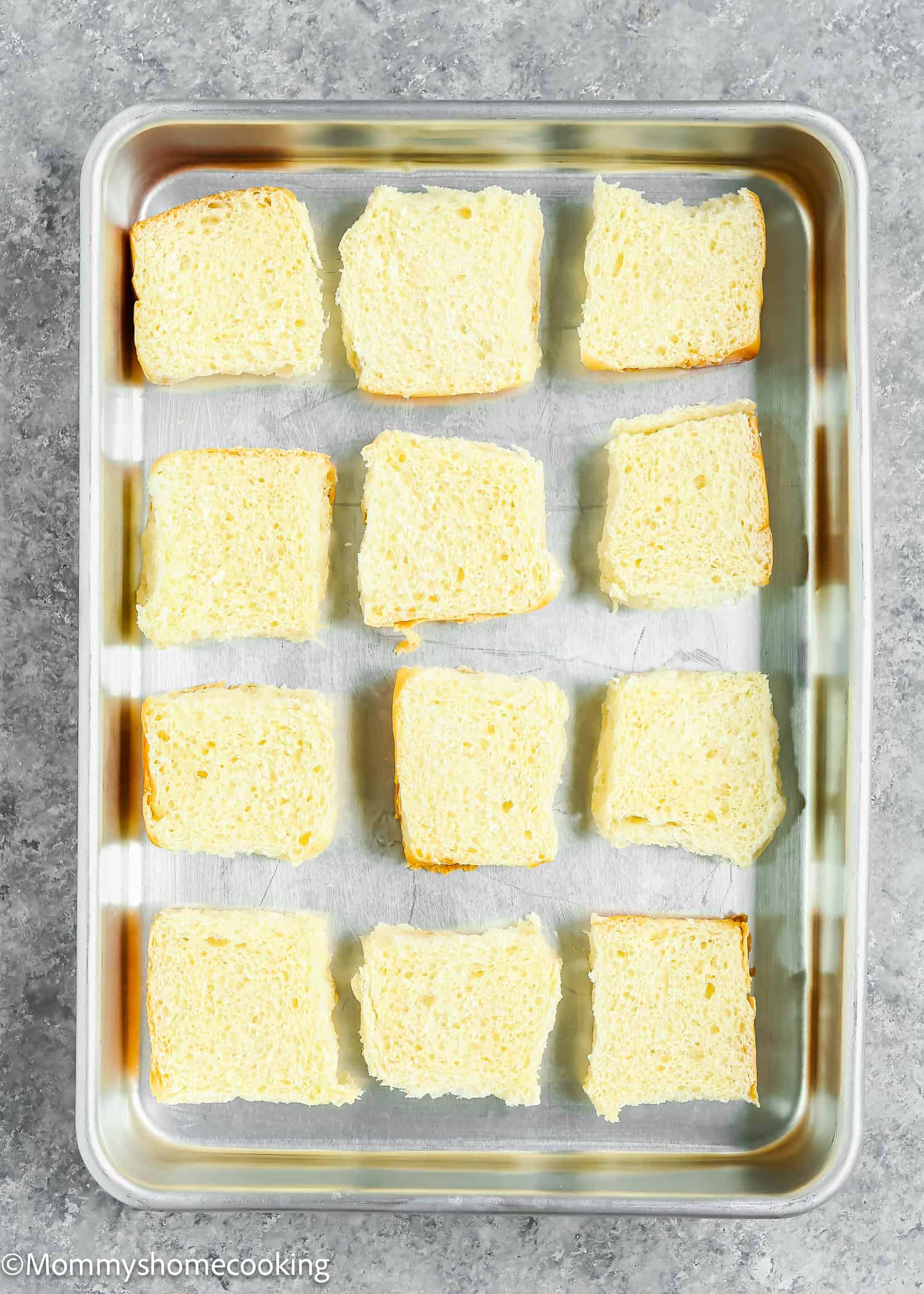 White bread slices are arranged evenly in a rectangular baking pan on a gray surface, perfect for crafting easy Cuban sliders ready in just 30 minutes.