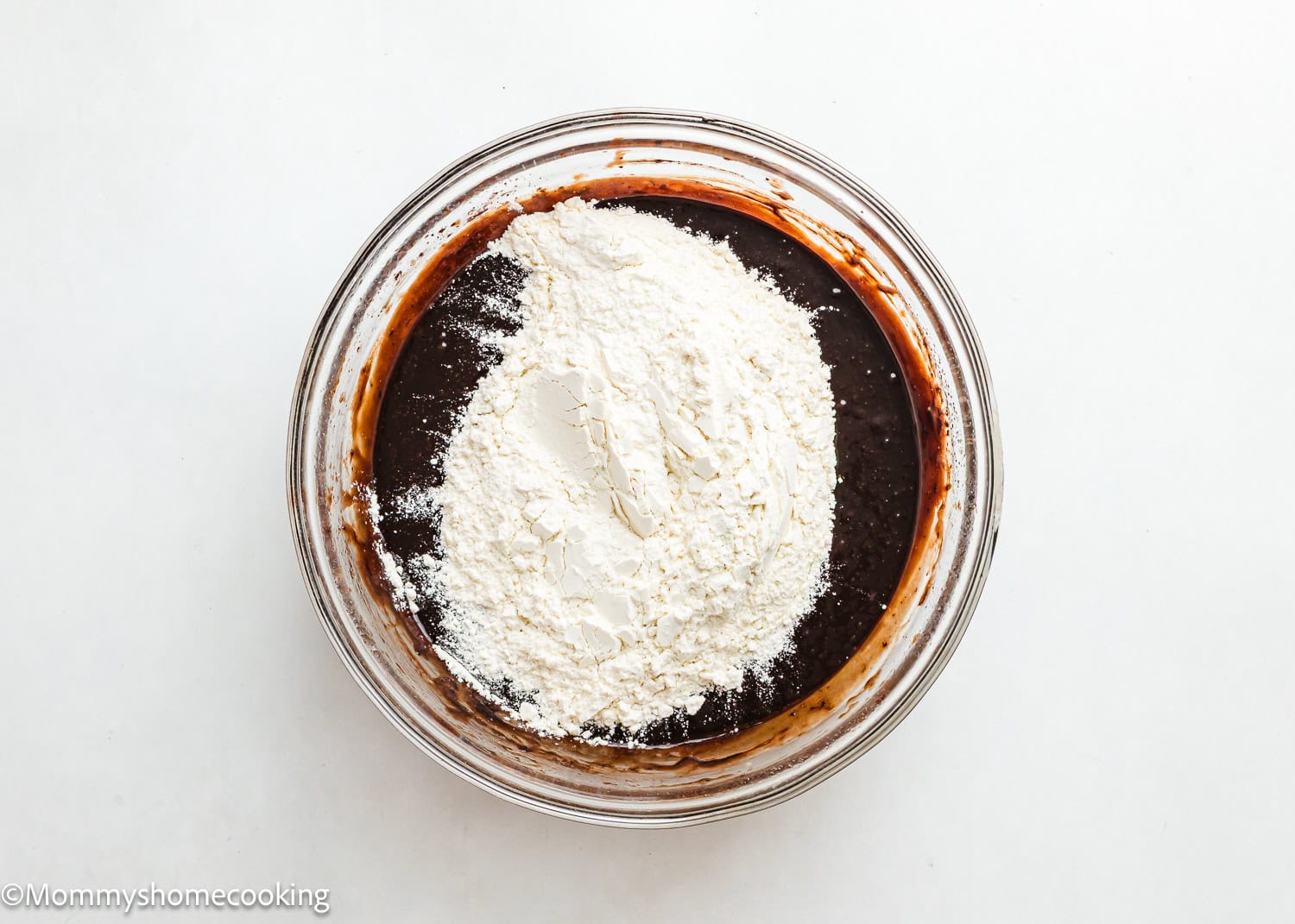 wet ingredients mix together in a bowl with dry ingredients on top to make brownies. 
