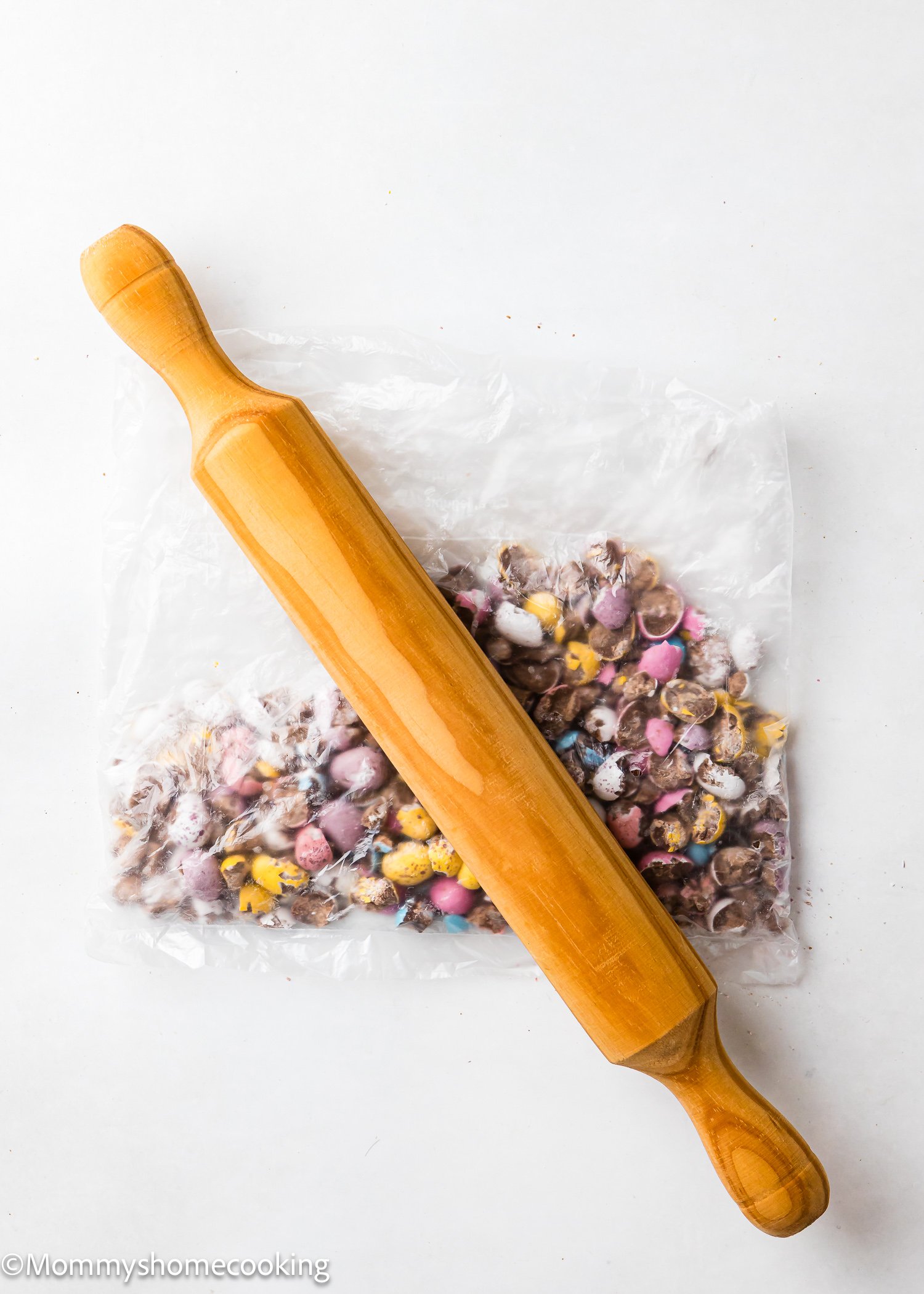 Cadbury Mini Eggs in a plastic bag with a rolling pin on top.