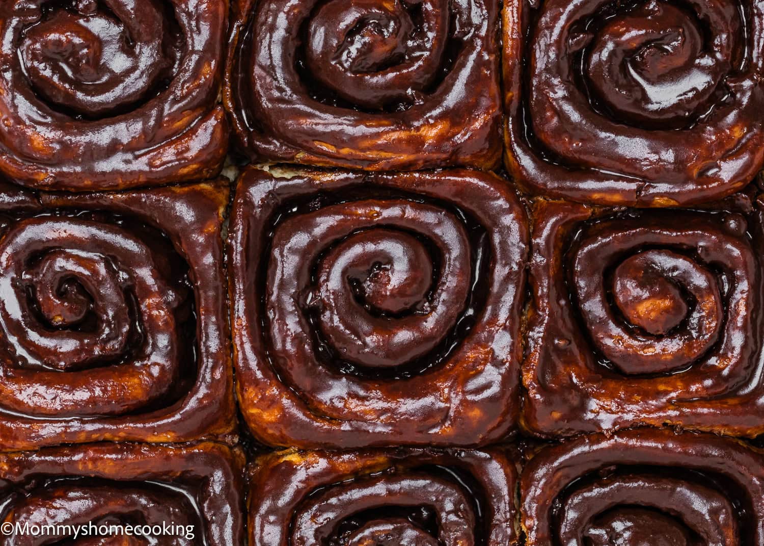 Close-up view of nine Eggless Chocolate Cinnamon Rolls with a rich chocolate glaze, arranged in a grid pattern.