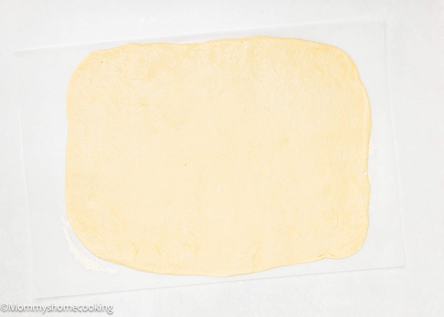Rectangular sheet of rolled-out dough for Eggless Chocolate Cinnamon Rolls placed on a sheet of parchment paper.
