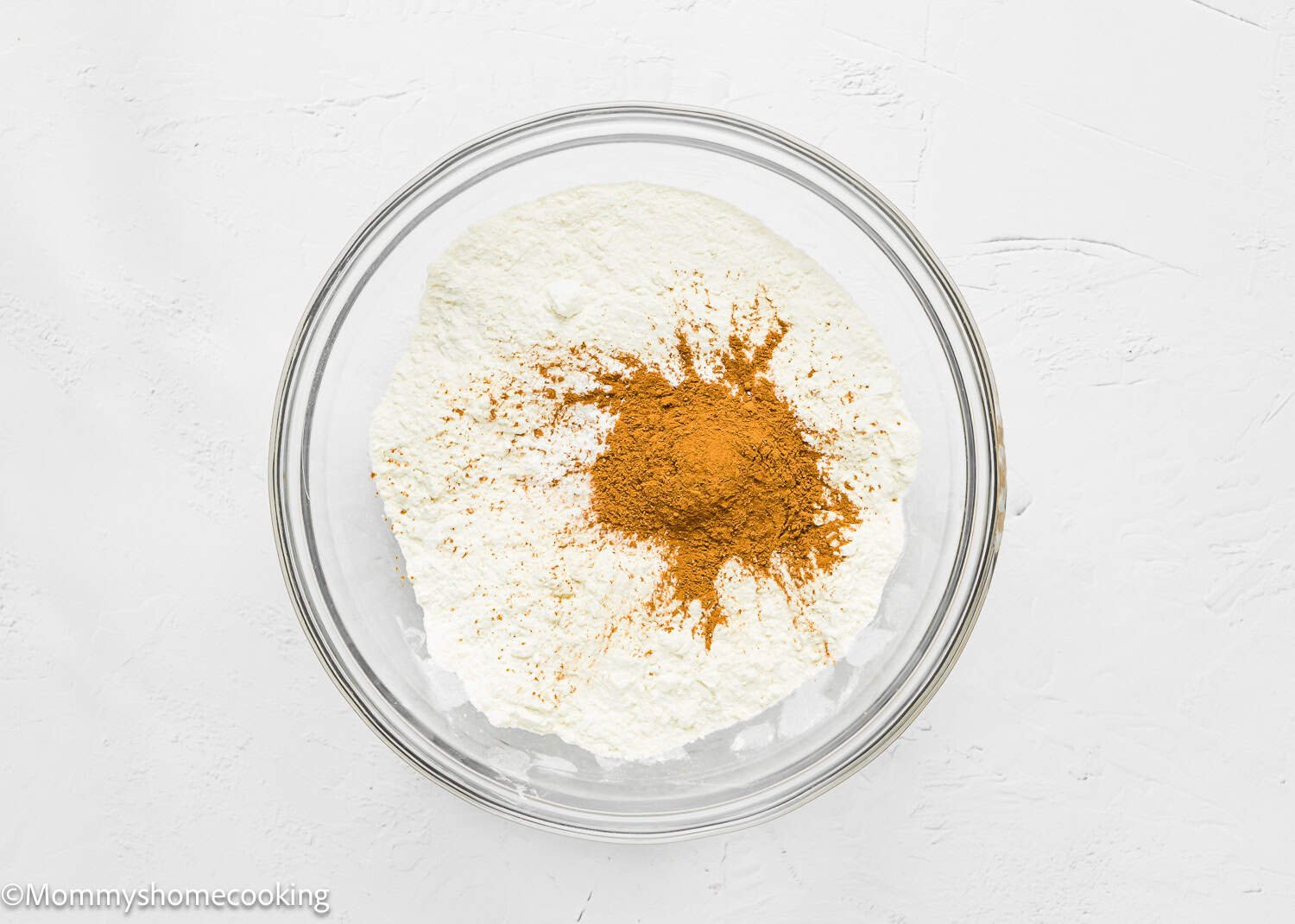A glass bowl containing dry ingredients, ready to make Eggless Hummingbird Bundt Cake.