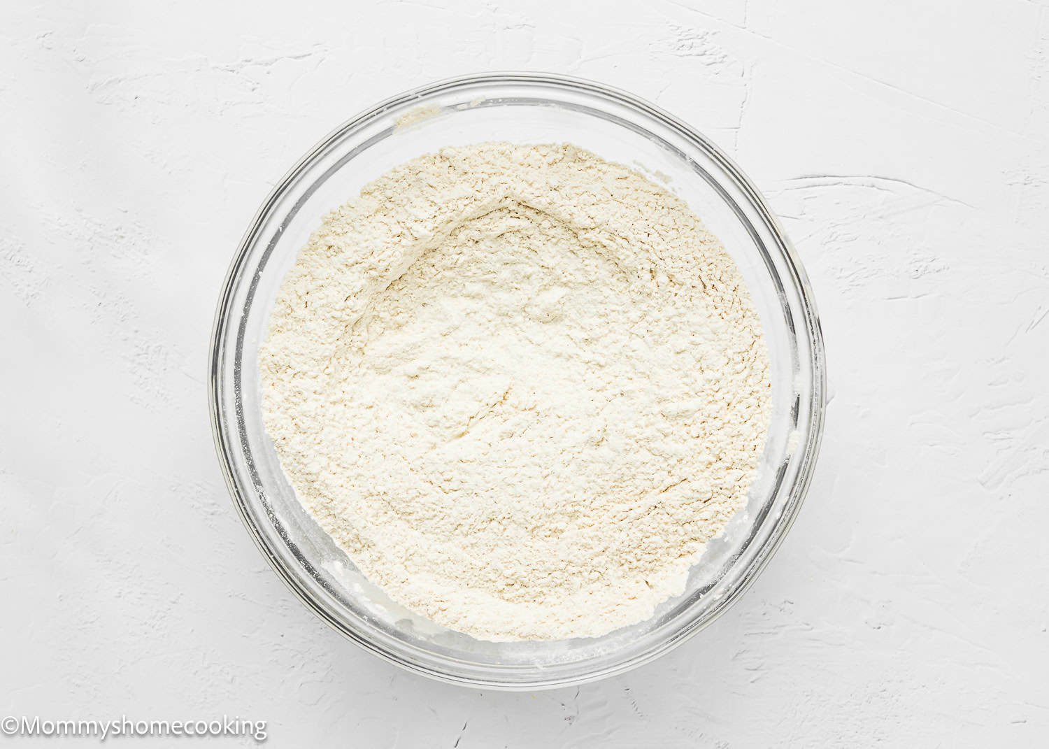 A glass bowl containing dry ingredients mix together, ready to make Eggless Hummingbird Bundt Cake.