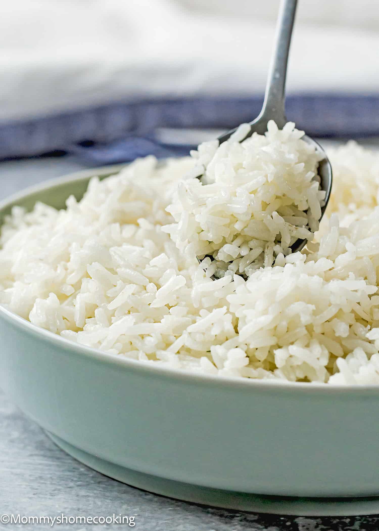 A bowl of cooked white rice with a spoon scooping some rice, perfect for anyone following the How To Cook Fluffy Rice On Stove (Beginner-Friendly Guide!).