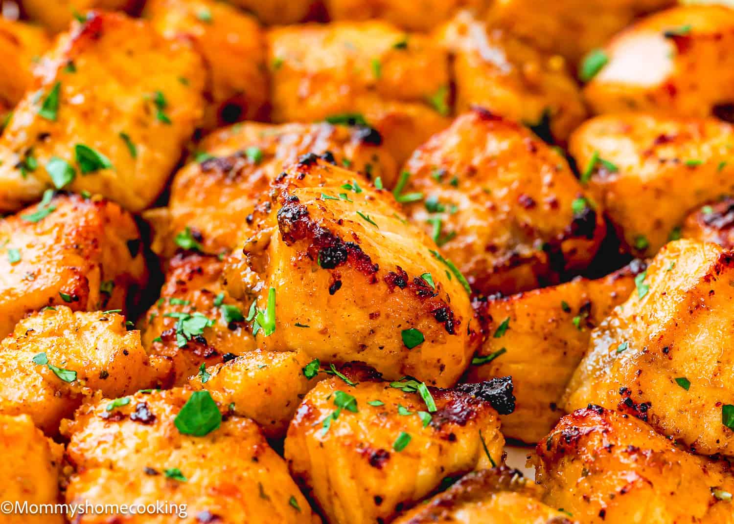 Close-up of grilled, seasoned chicken pieces garnished with chopped parsley, perfect for serving alongside Easy Air Fryer Salmon Bites.