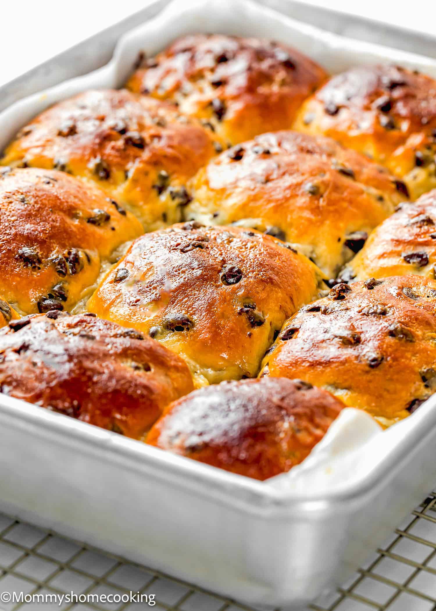 A tray of freshly baked Eggless Chocolate Chip Brioche Rolls, golden brown on top, arranged closely together in a metal baking pan.