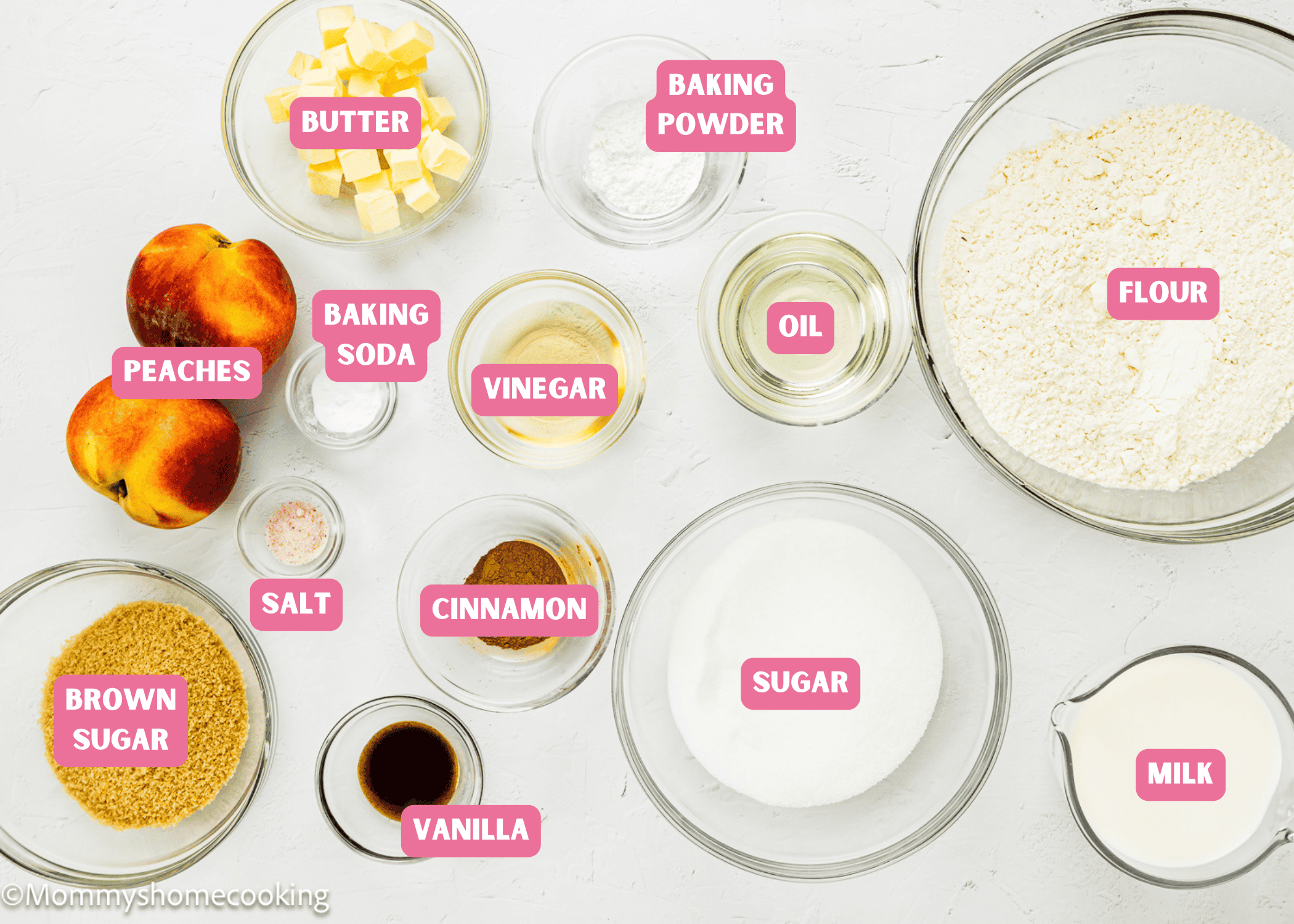 Various labeled ingredients for baking Eggless Peach Coffee Cake, including flour, sugar, milk, butter, oil, peaches, brown sugar, baking powder, baking soda, vinegar, salt, cinnamon, and vanilla on a white surface.