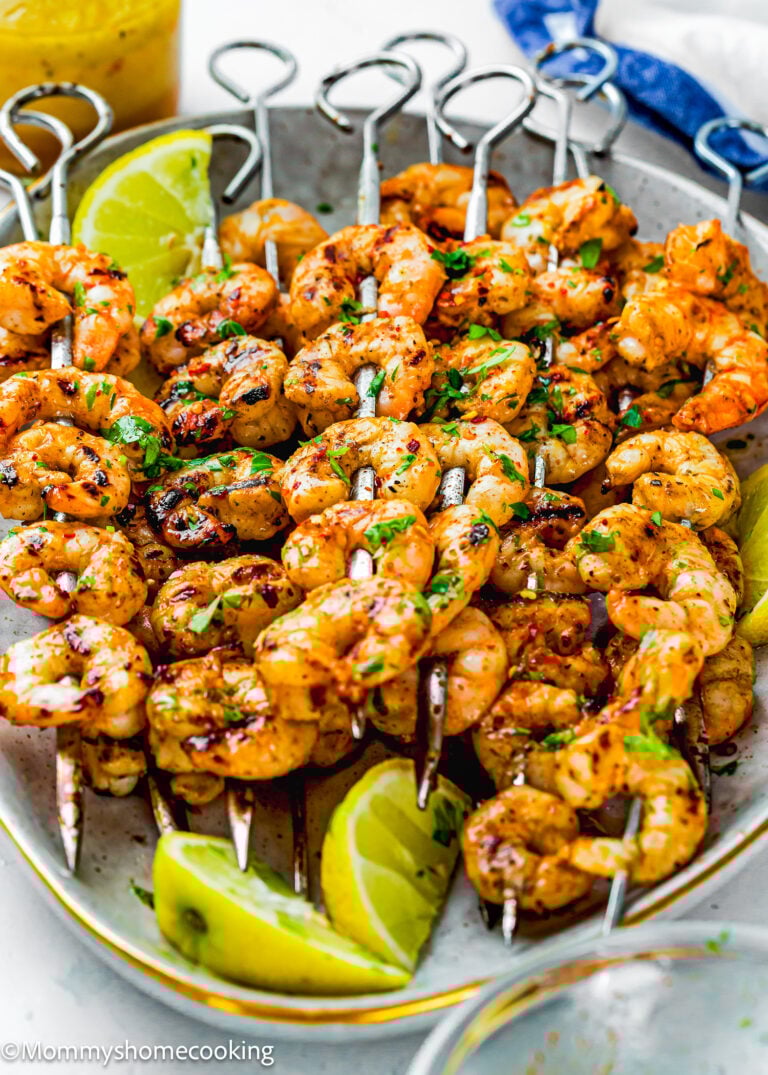 Grilled Shrimp with Simple Seasoning skewers garnished with herbs, served on a plate with lime wedges.
