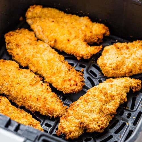 Six Easy Air Fryer Chicken Tenders (No Eggs - No Dairy) are arranged in a black air fryer basket, cooked to a golden brown.