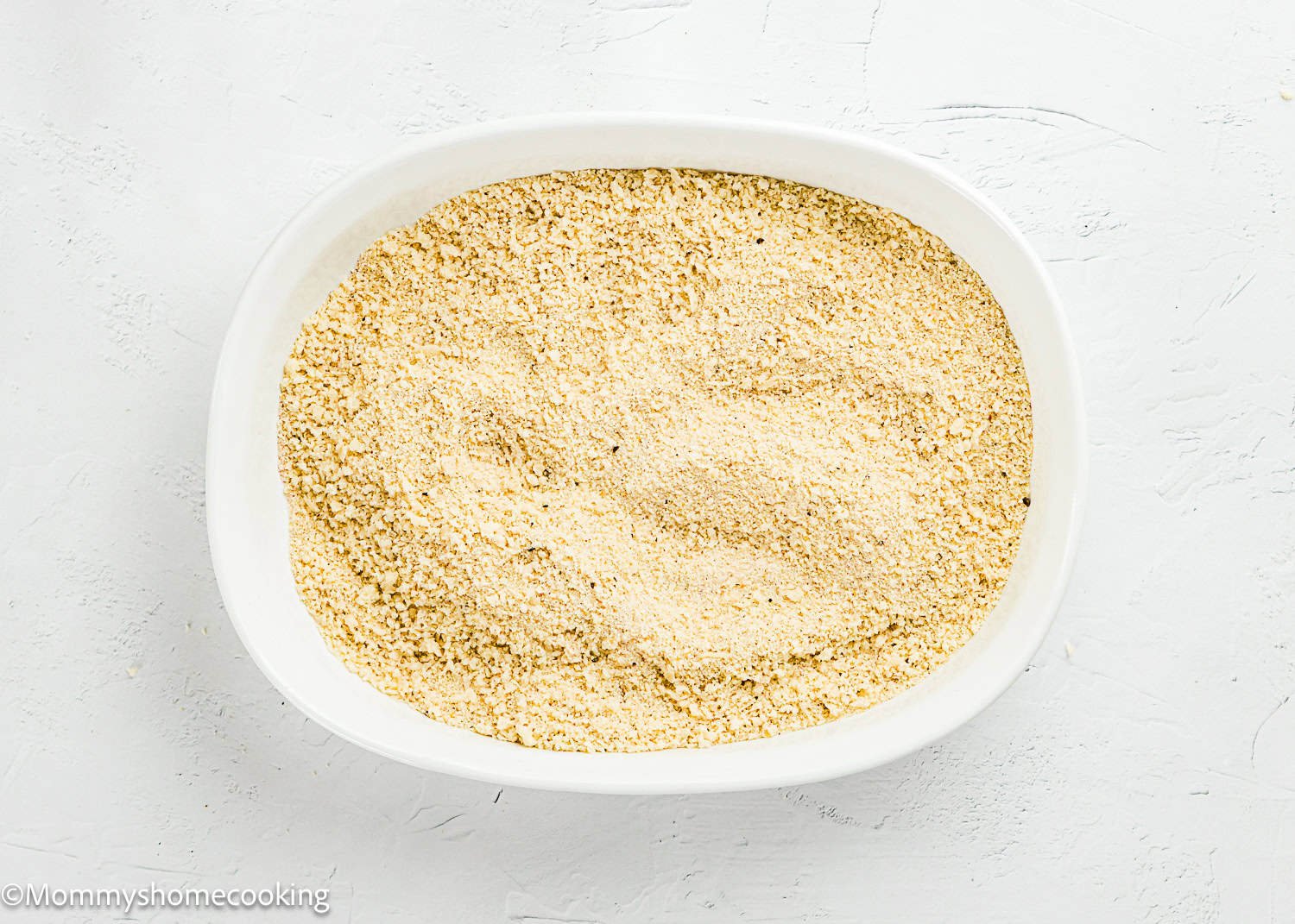 A white oval dish filled with fine, light beige breadcrumbs on a white textured surface—perfect for making Easy Air Fryer Chicken Tender (No Eggs - No Dairy).