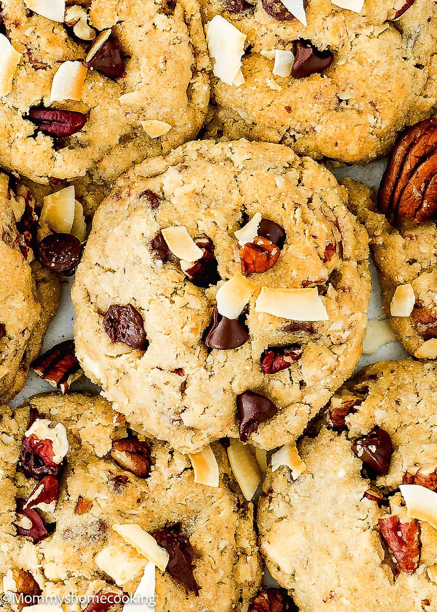 A close-up of Eggless Cowboy Cookies topped with chocolate chunks, pecans, and coconut flakes.