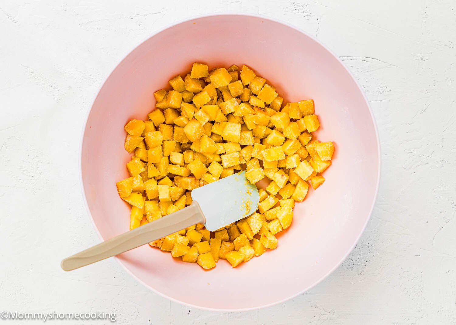 A pink bowl filled with diced peach pieces and sugar and flour, alongside a white spatula—perfect inspiration for an Eggless Peach Coffee Cake.