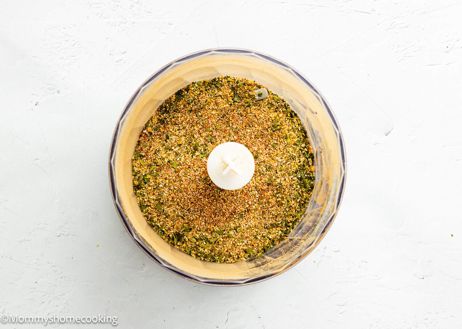 A spice grinder filled with Easy Homemade Everyday Seasoning (All-Purpose & Allergy-Safe) sits on a light textured surface, viewed from above.