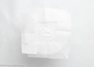 A small amount of dough for an egg-free vanilla cake sits in the center of a plate, covered by overlapping sheets of white parchment paper.