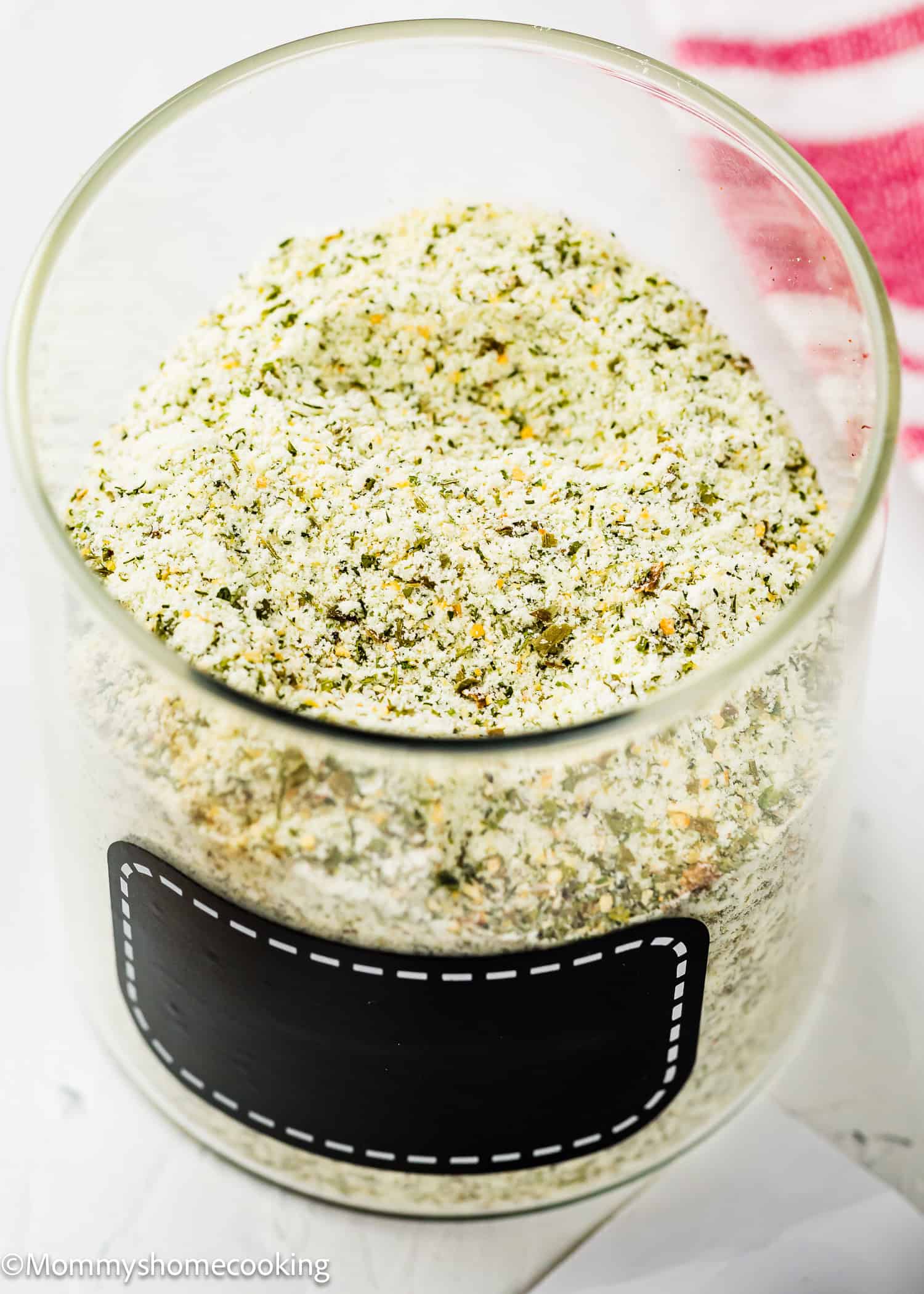 A glass jar filled with a dry, green and white Homemade Ranch Seasoning Mix (Allergy-Friendly & Dairy-Free Option!), labeled with a blank black label.