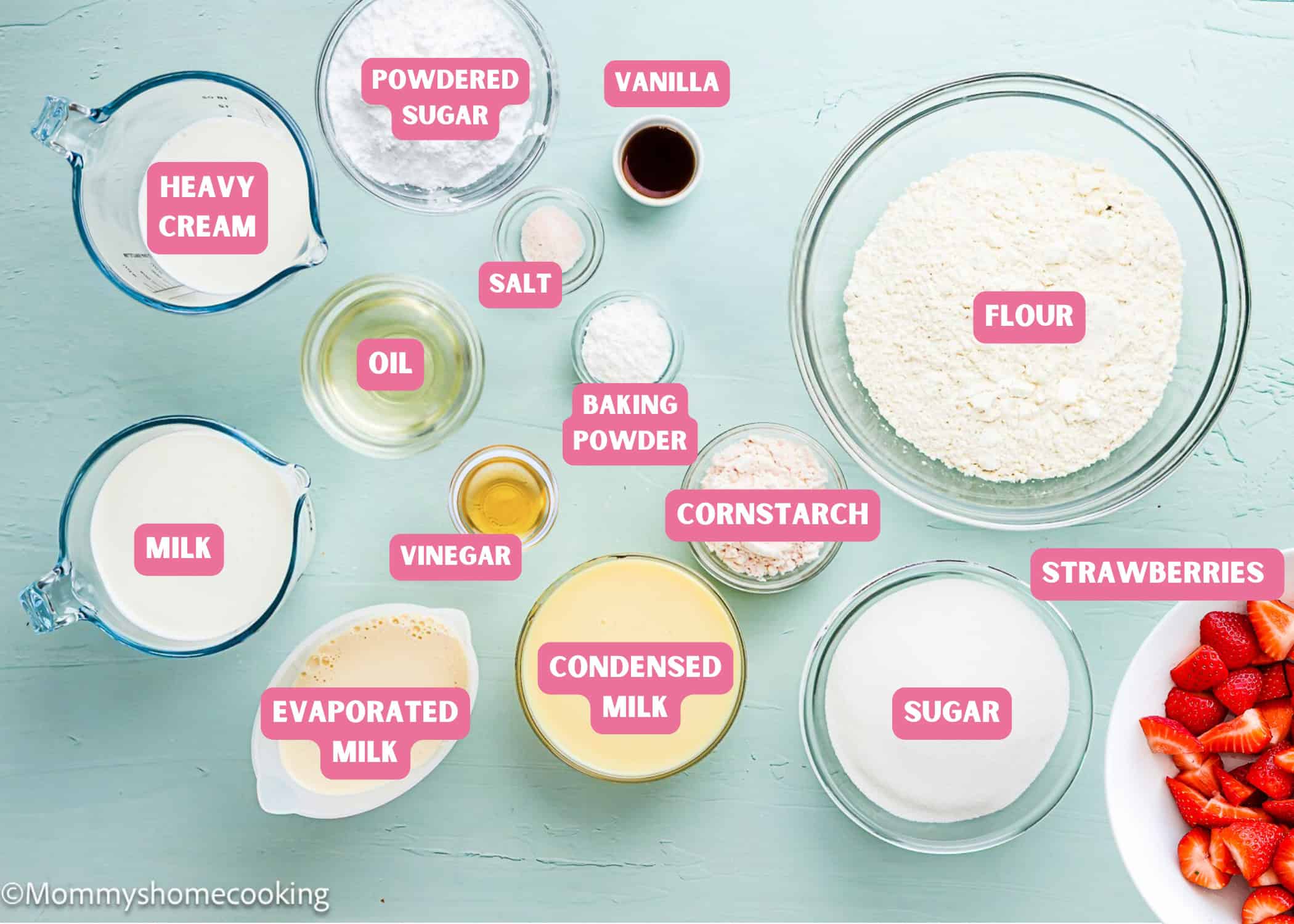 Various baking ingredients in bowls and containers, including flour, sugar, milk, evaporated milk, condensed milk, heavy cream, oil, and strawberries—perfect for making The Best Eggless Tres Leches Cake.
