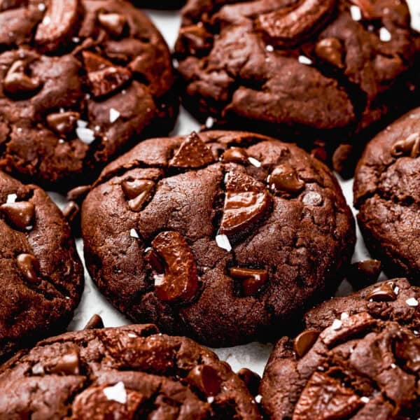 Close-up of several Ultimate Chocolate Cookies (Egg-Free) with chocolate chunks and small sea salt flakes on top.