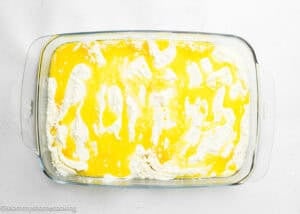 Rectangular glass baking dish filled with Ultimate Easy Peach Dump Cake (5 Ingredients) mix, topped with melted butter and patches of dry flour.