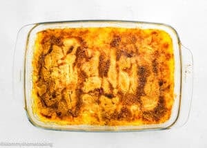 A rectangular glass baking dish filled with golden-brown Ultimate Easy Peach Dump Cake (5 Ingredients) on a white surface.