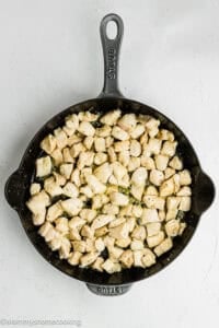 Cubed pieces of cooked chicken breast in a black cast iron skillet, viewed from above on a white surface—perfect for adding to Easy Lemon Chicken Orzo (One Pot).