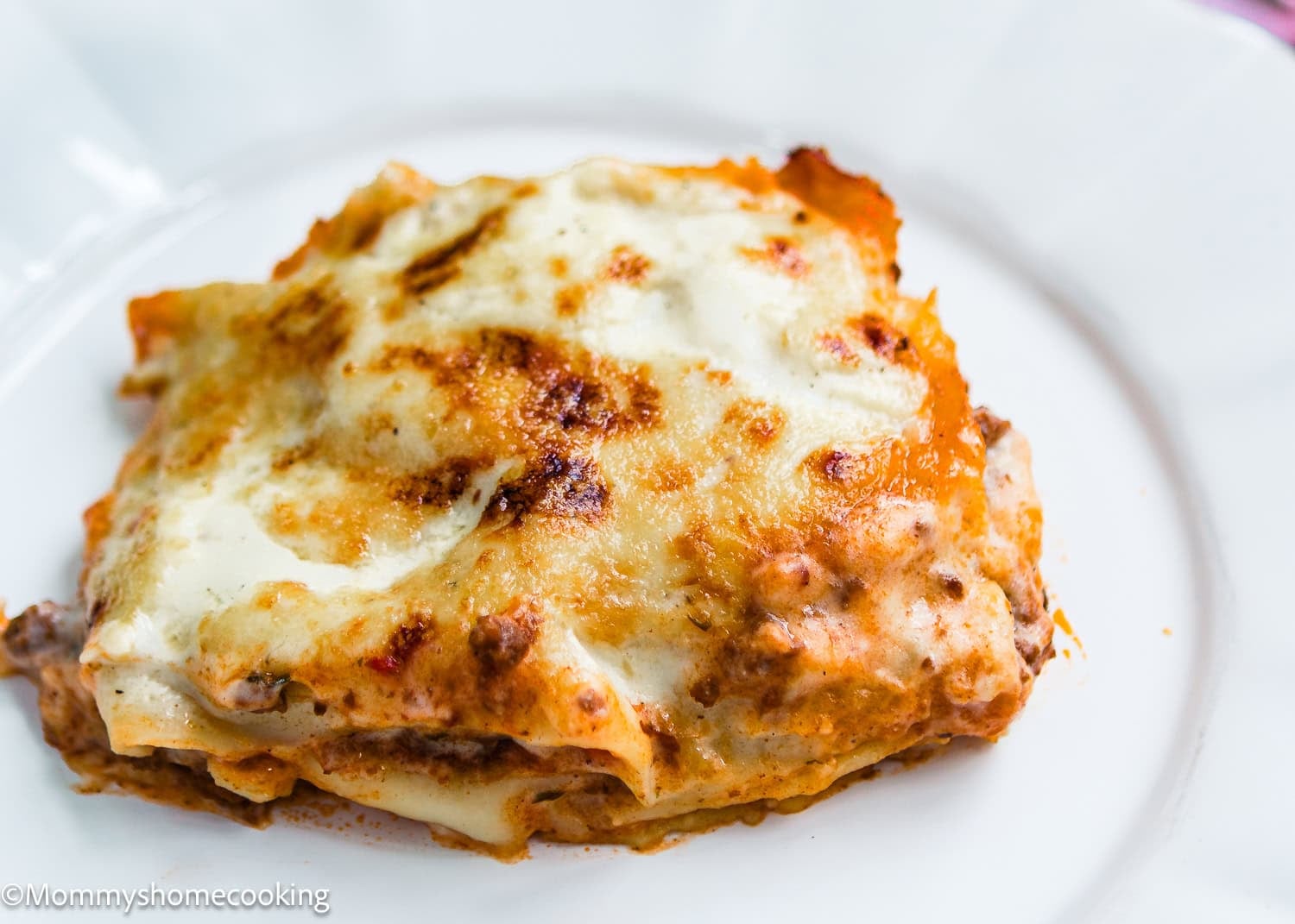 A slice of Easy Venezuelan Pasticho with layers of pasta, meat sauce, and melted cheese is served on a white plate.