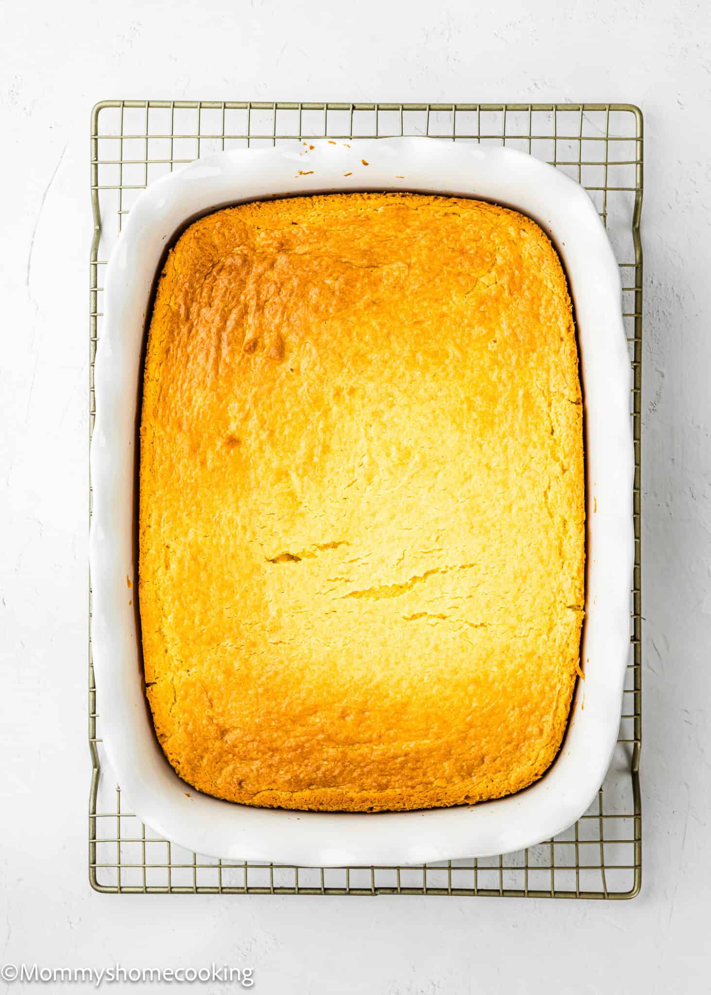 baked Eggless Lemon Poke Cake over a cooling rack.
