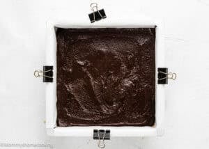 Rich homemade chocolate brownie batter in a square baking pan ready for baking.