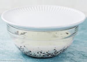 A glass bowl with a white plate on top, containing chocolate and cream, sits on a blue surface—perfect as a base for your foolproof chocolate ganache (with dairy-free option!).