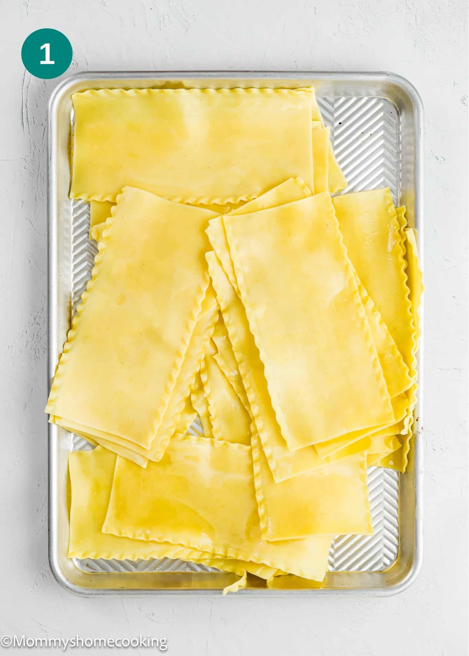 A baking sheet filled with cooked lasagna noodles arranged in overlapping layers.