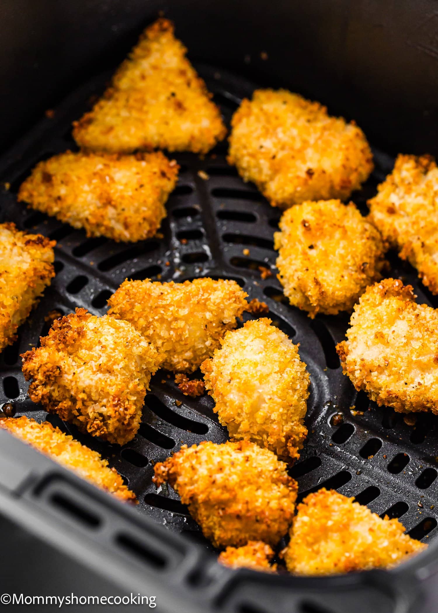 Breaded and crispy Garlic Parmesan Chicken Bites are arranged in a single layer inside an air fryer basket, ready to be cooked or just finished cooking. The bites have a golden-brown, crunchy coating.