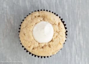 An Eggless Cannoli Cupcake with a creamy center, shown from above on a light-colored surface.