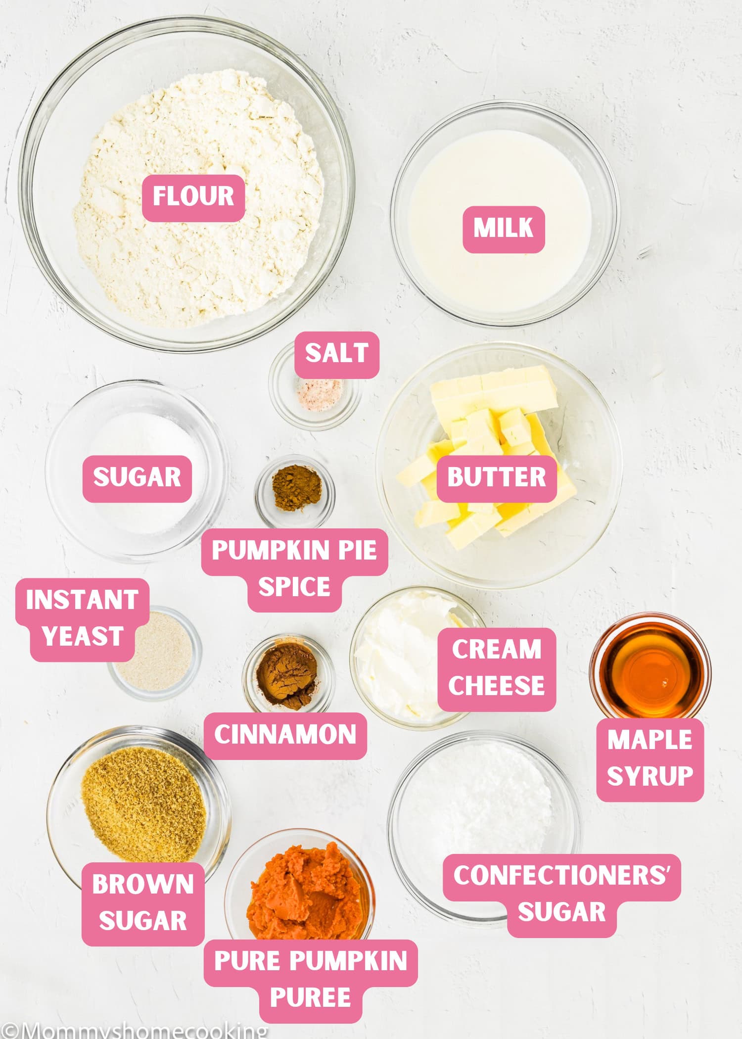 An overhead view of labeled bowls filled with flour, milk, butter, sugar, instant yeast, pumpkin puree, spices, cream cheese, and maple syrup—perfect for making Eggless Pumpkin Cinnamon Rolls.