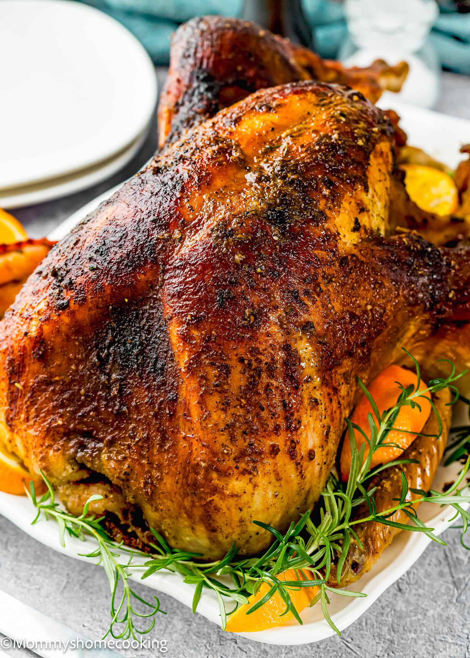 A whole roasted turkey with crispy, seasoned skin is served on a platter garnished with fresh rosemary and orange slices—Not a Classic Boring Turkey: Citrus-Garlic Chipotle Thanksgiving Turkey Recipe.